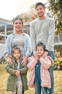 Buy stock photo Shot of a young couple and their two daughters standing outside their home