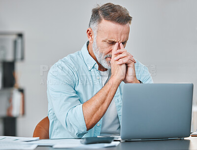 Buy stock photo Shot of a mature businessman sitting alone in his office and feeling stressed while using his laptop