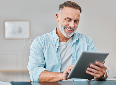 Buy stock photo Shot of a mature businessman sitting alone in his office and using a digital tablet