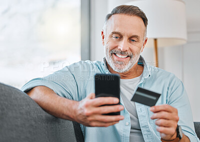 Buy stock photo Shot of a mature man sitting alone on his sofa at home and using his cellphone for online shopping