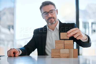 Buy stock photo Shot of a mature businessman working with wooden building blocks in a modern office
