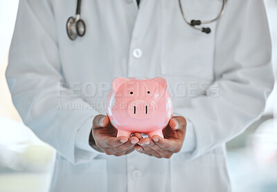 Buy stock photo Shot of a unrecognizable doctor  holding a piggy bank in a office