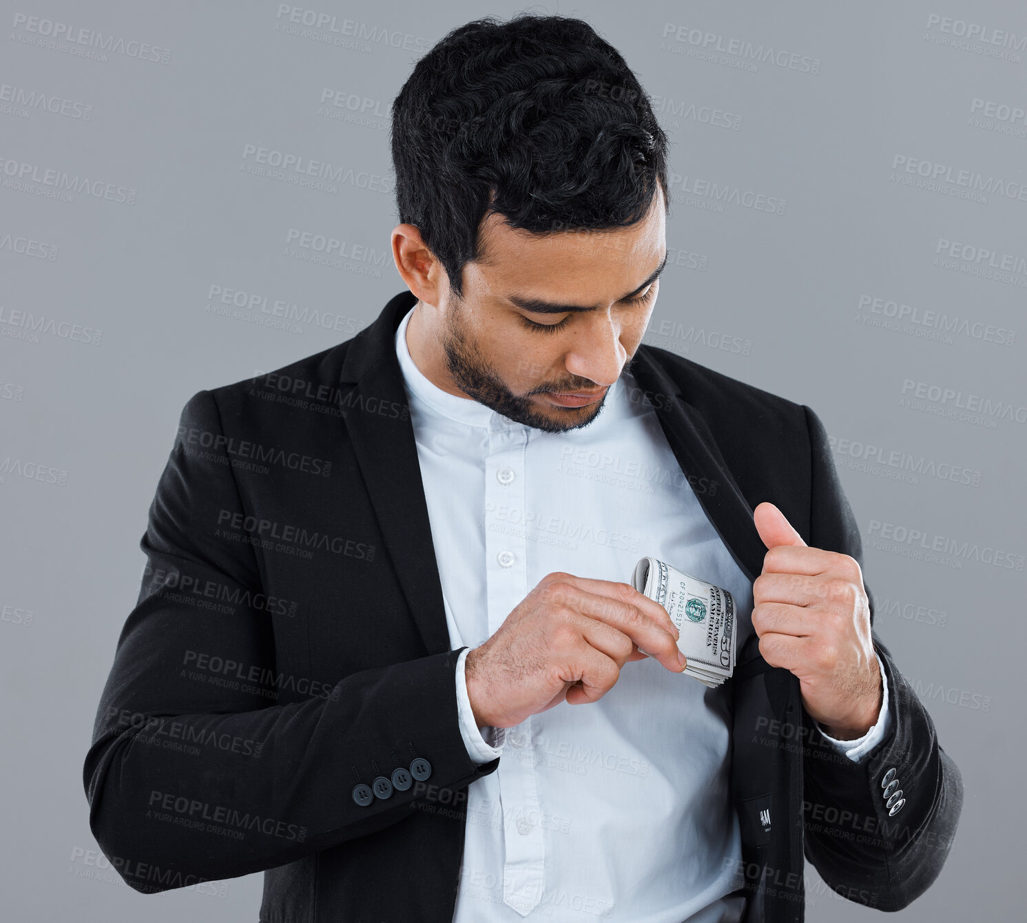 Buy stock photo Shot of a businessman slipping money into his pocket against a grey background