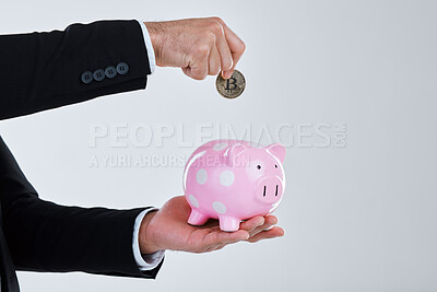 Buy stock photo Shot of an unrecognizable businessman depositing coins into his piggy bank against a grey background