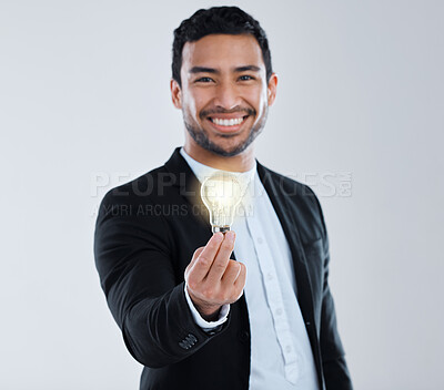 Buy stock photo Shot of a young man holding a light bulb against a grey background