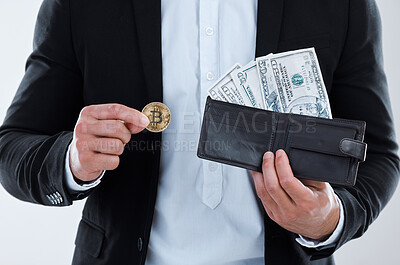Buy stock photo Closeup shot of an unrecognisable businessman holding a bitcoin and a wallet filled with banknotes against a white background