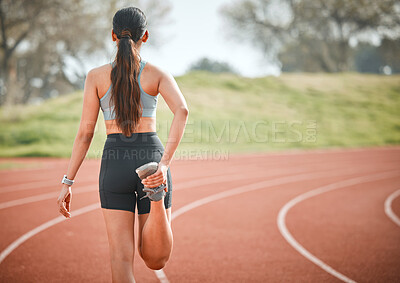 Buy stock photo Rearview shot of a young athlete stretching her legs on a running track outdoors