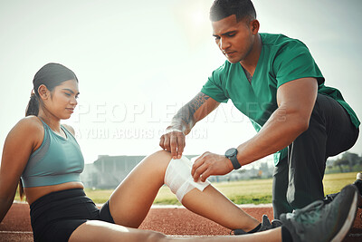 Buy stock photo Shot of a sports paramedic providing first aid to an athlete on a running track