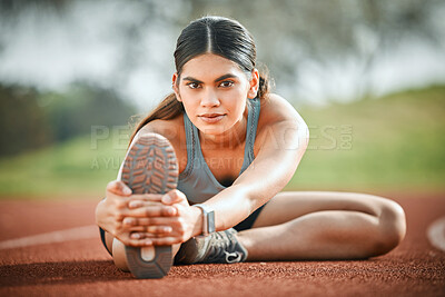 Buy stock photo Portrait of a young athlete stretching her legs on a running track outdoors