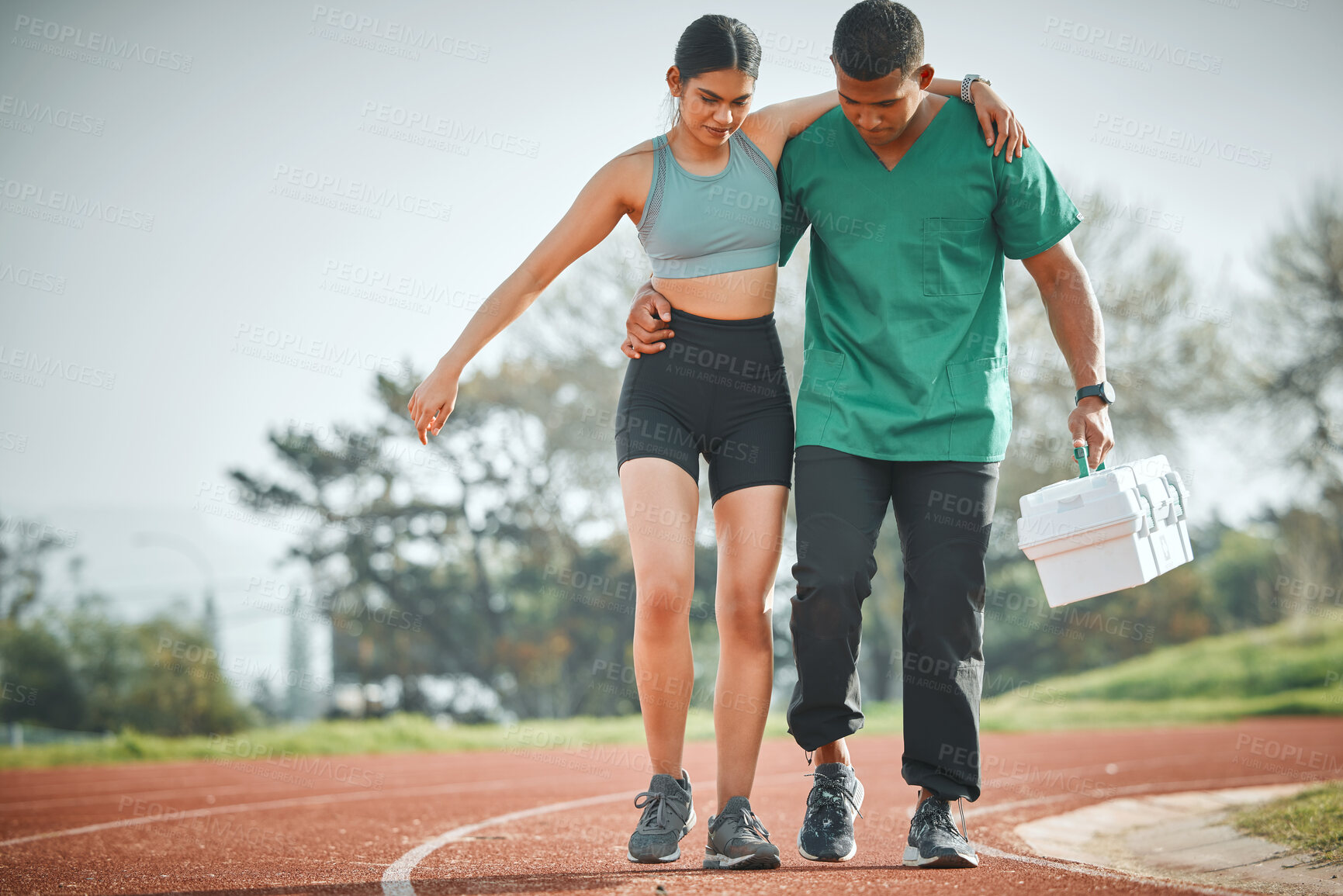 Buy stock photo Shot of a sports paramedic providing first aid to an athlete on a running track