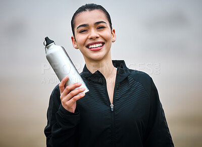 Buy stock photo Cropped portrait of an attractive young female athlete holding her water bottle while standing outside