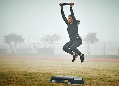 Buy stock photo Shot of a sporty young woman exercising on a step with a weight plate outdoors
