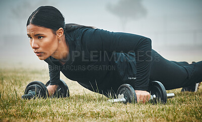 Buy stock photo Shot of a sporty young woman exercising with dumbbells outdoors