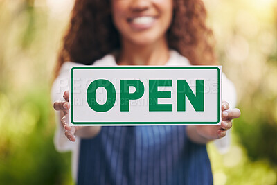 Buy stock photo Shot of a young woman holding a sign stating that her nursery is open