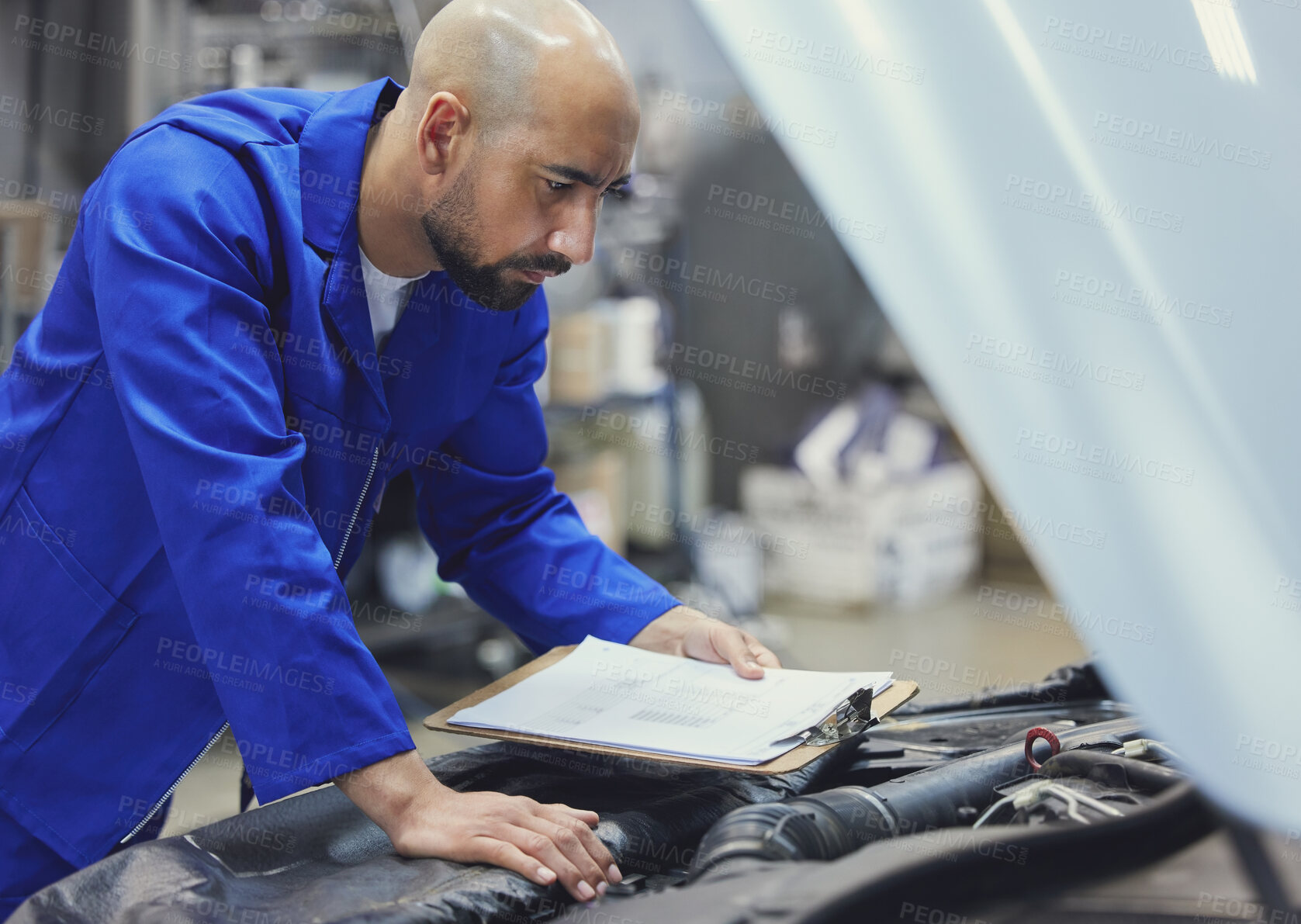 Buy stock photo Cropped shot of a handsome young male mechanic working on the engine of a car during a service