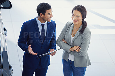 Buy stock photo Cropped shot of a handsome young male car salesman talking to a female customer on the showroom floor