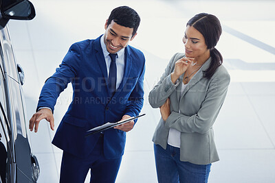 Buy stock photo Cropped shot of a handsome young male car salesman talking to a female customer on the showroom floor