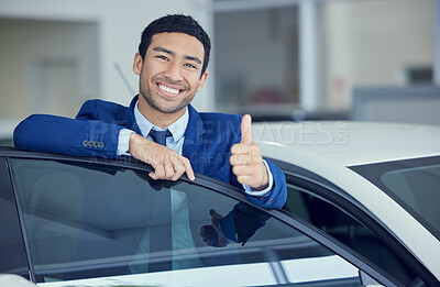 Buy stock photo Cropped portrait of a handsome young male car salesman giving thumbs up towards the camera while working on the showroom floor
