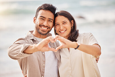 Buy stock photo Couple, portrait and love sign with hands at the ocean for travel with sunshine with a smile. Beach, together and heart with hand and smile in the summer for a weekend with romance.