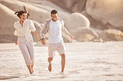 Buy stock photo Shot of a young couple holding hands while running on the beach