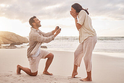 Buy stock photo Couple, engagement proposal and surprise at beach with smile, happiness or love on vacation in sunset. Man, woman and ring with marriage offer by ocean with smile, excited face or together on holiday