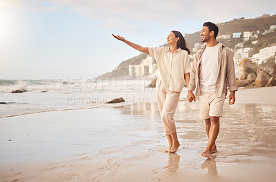 Buy stock photo Mockup, pointing and a couple holding hands on the beach while walking together on a date for romance. Love, happy or smile with a man and woman taking a romantic walk by the coastal ocean or sea