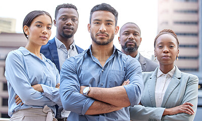 Buy stock photo Shot of a group of businesspeople standing with their arms crossed against a city background