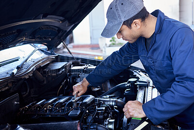 Buy stock photo High angle shot of a handsome young male mechanic working on the engine of a car during a service