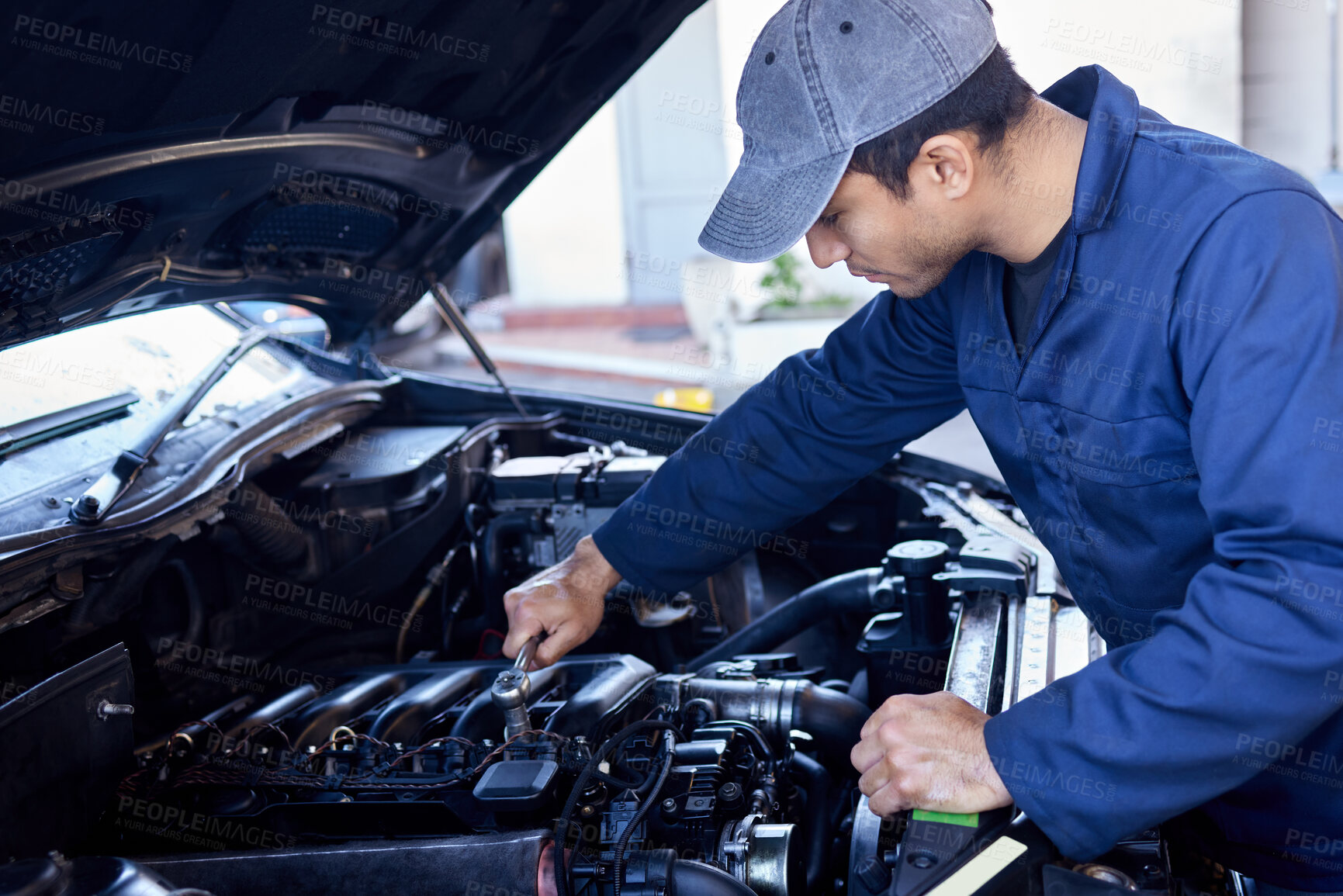 Buy stock photo High angle shot of a handsome young male mechanic working on the engine of a car during a service