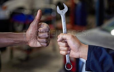 Buy stock photo Closeup shot of one mechanic holding a spanner and another giving thumbs up in their workshop