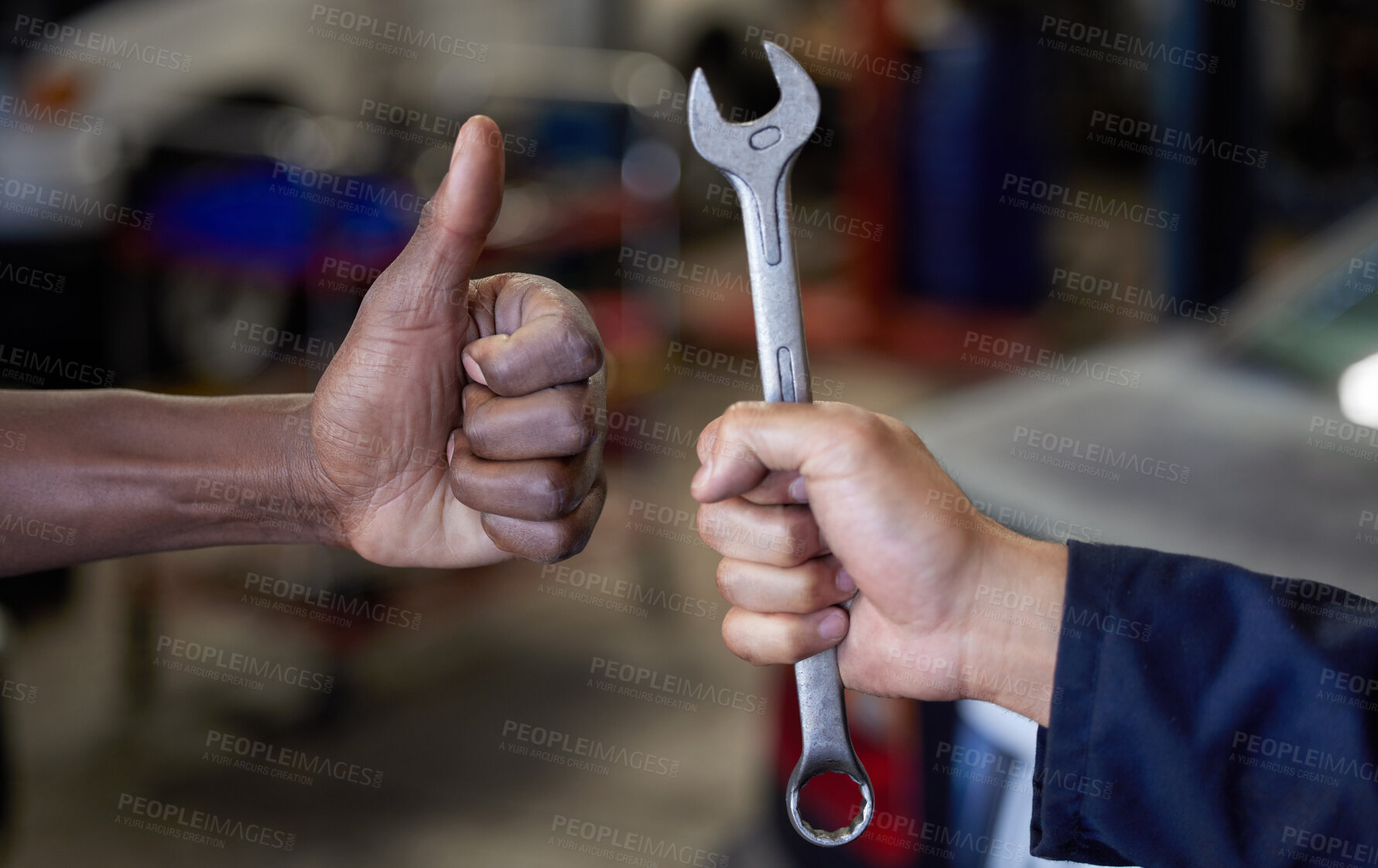 Buy stock photo Closeup shot of one mechanic holding a spanner and another giving thumbs up in their workshop