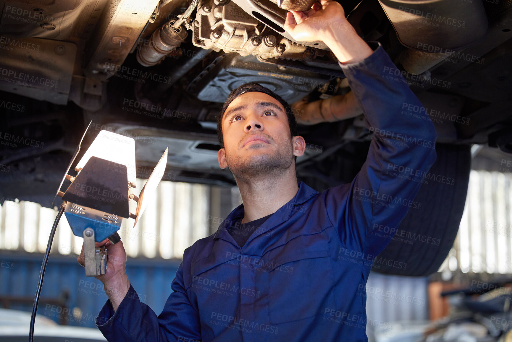 Buy stock photo Man, mechanic and check under car, repair workshop and automotive engineering for car maintenance. Professional, vehicle lift and motor service for issues, exhaust system and suspension inspection