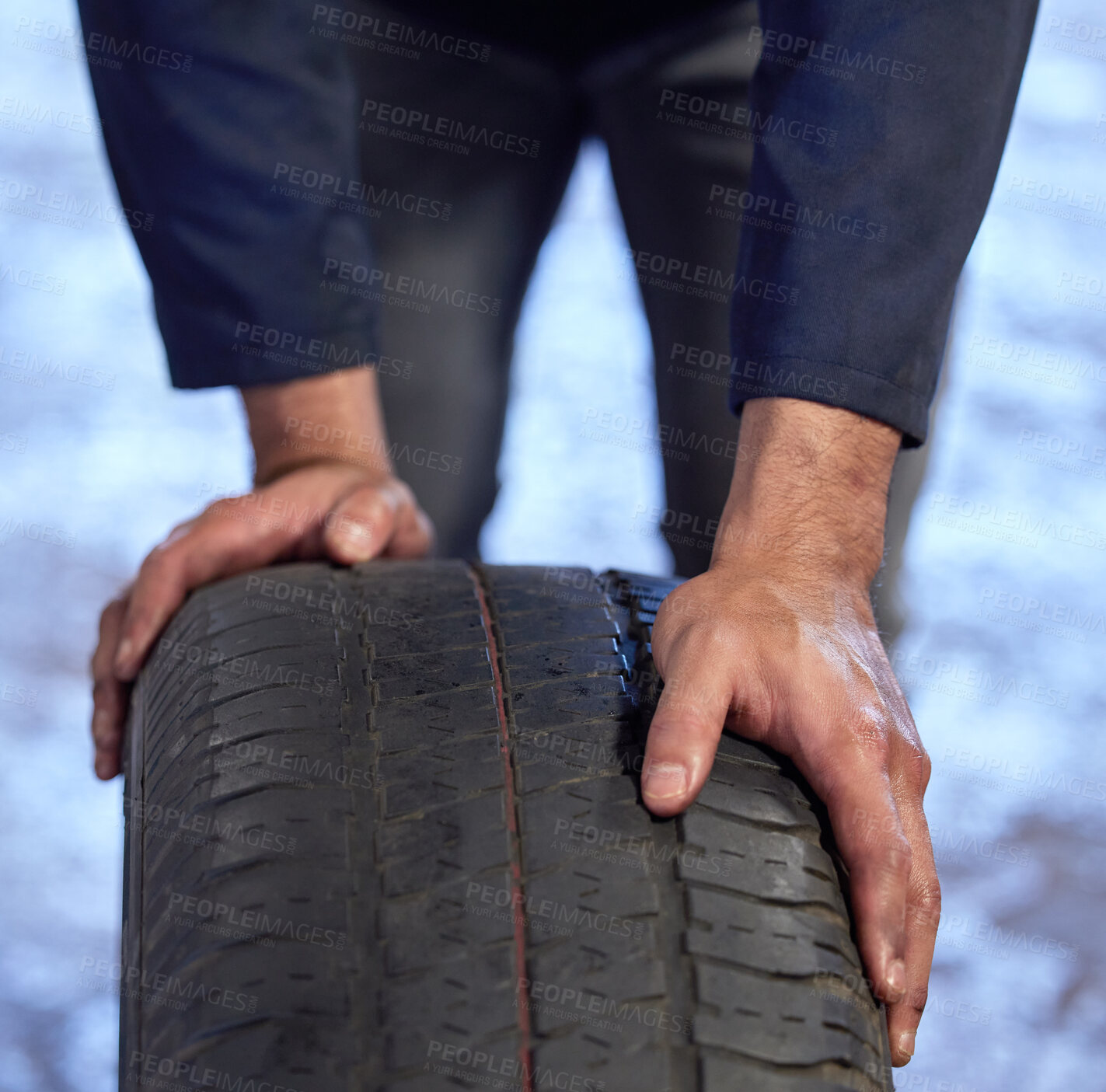 Buy stock photo High angle shot of an unrecognizable male mechanic rolling a tyre through his workshop during a service