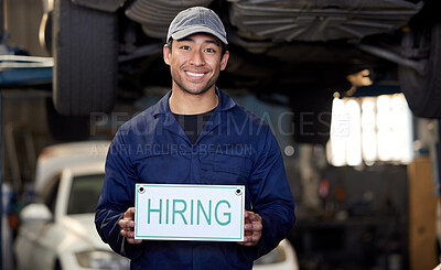 Buy stock photo Cropped portrait of a handsome young male mechanic holding a hiring sign while standing in his workshop