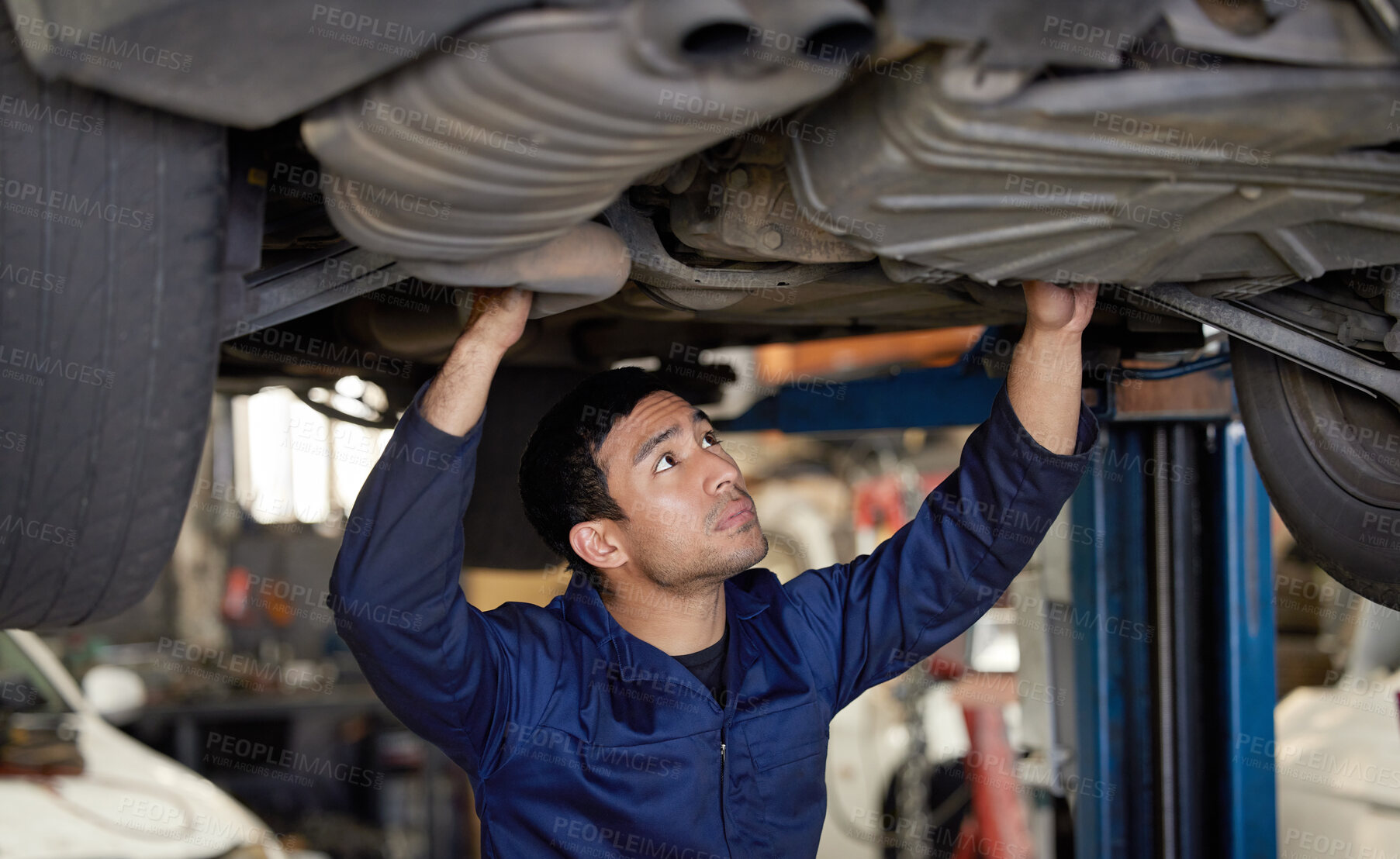 Buy stock photo Cropped shot of a handsome young male mechanic working on the engine of a car during a service