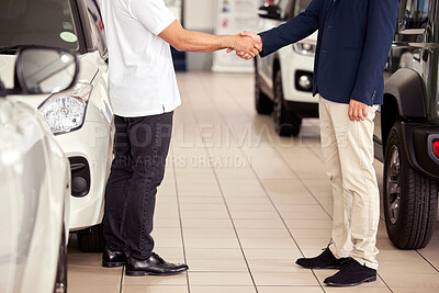 Buy stock photo Cropped shot of a car salesman shaking hands with a client on the showroom floor