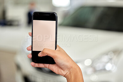 Buy stock photo Cropped shot of a woman taking picture on her cellphone at a car dealership