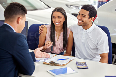 Buy stock photo Shot of a young couple consulting with a car salesman