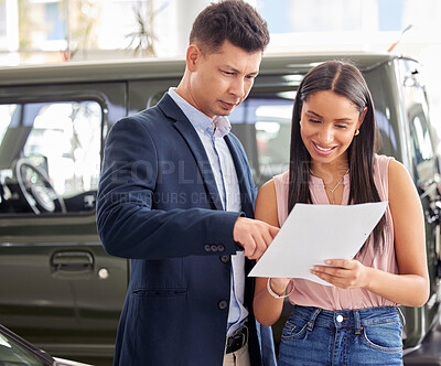 Buy stock photo Shot of a car salesman and a customer looking at paperwork