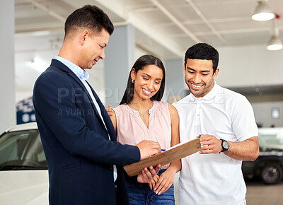Buy stock photo Shot of a car salesman assisting a young couple on the showroom floor