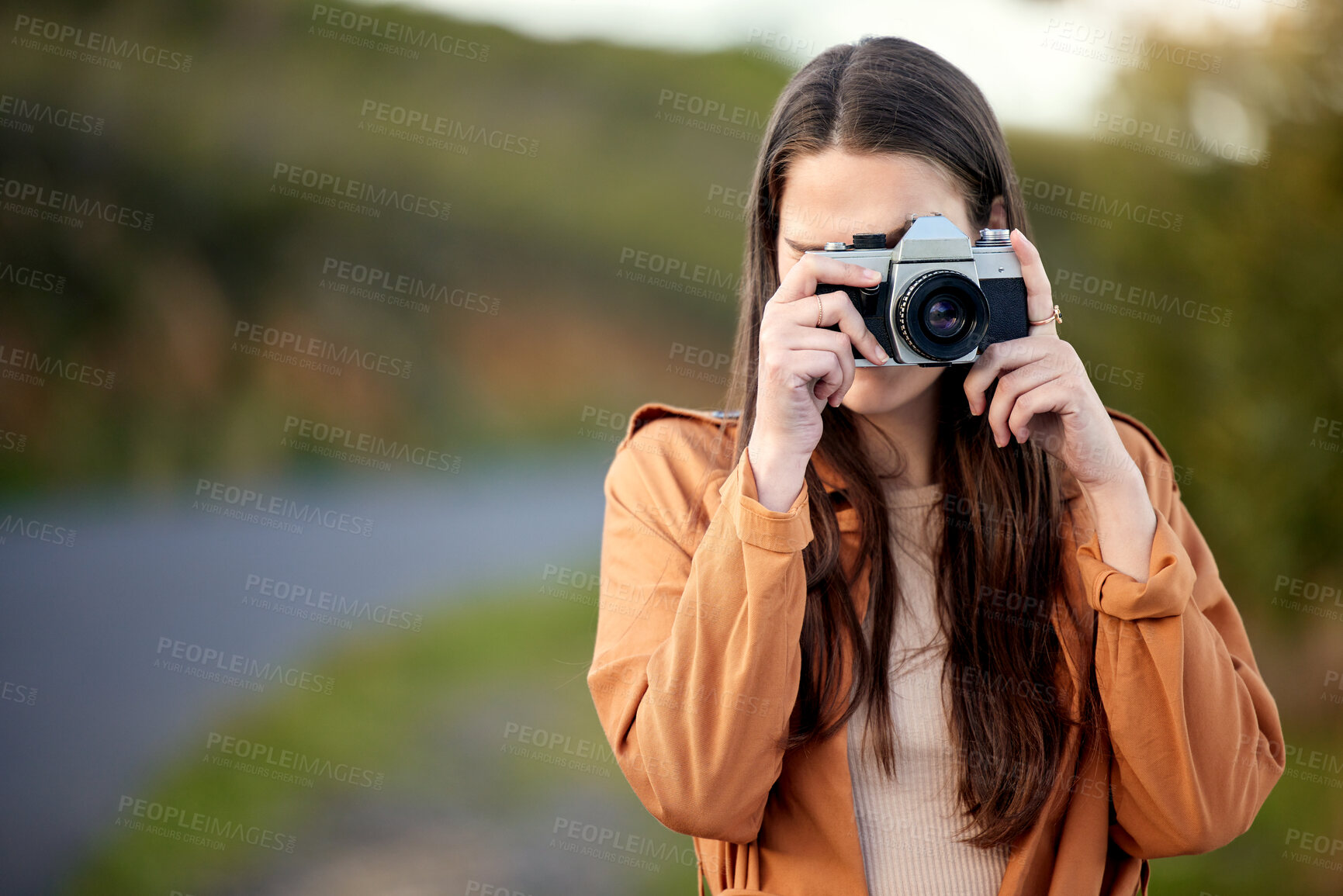 Buy stock photo Shot of a young woman using her camera while spending time outdoors