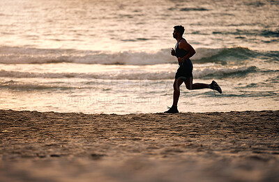 Buy stock photo Shot of a sporty young man running along the beach