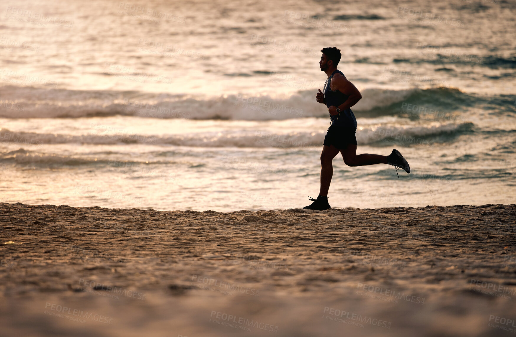 Buy stock photo Shot of a sporty young man running along the beach