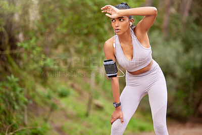 Buy stock photo Shot of a young woman taking a break while jogging through the forest