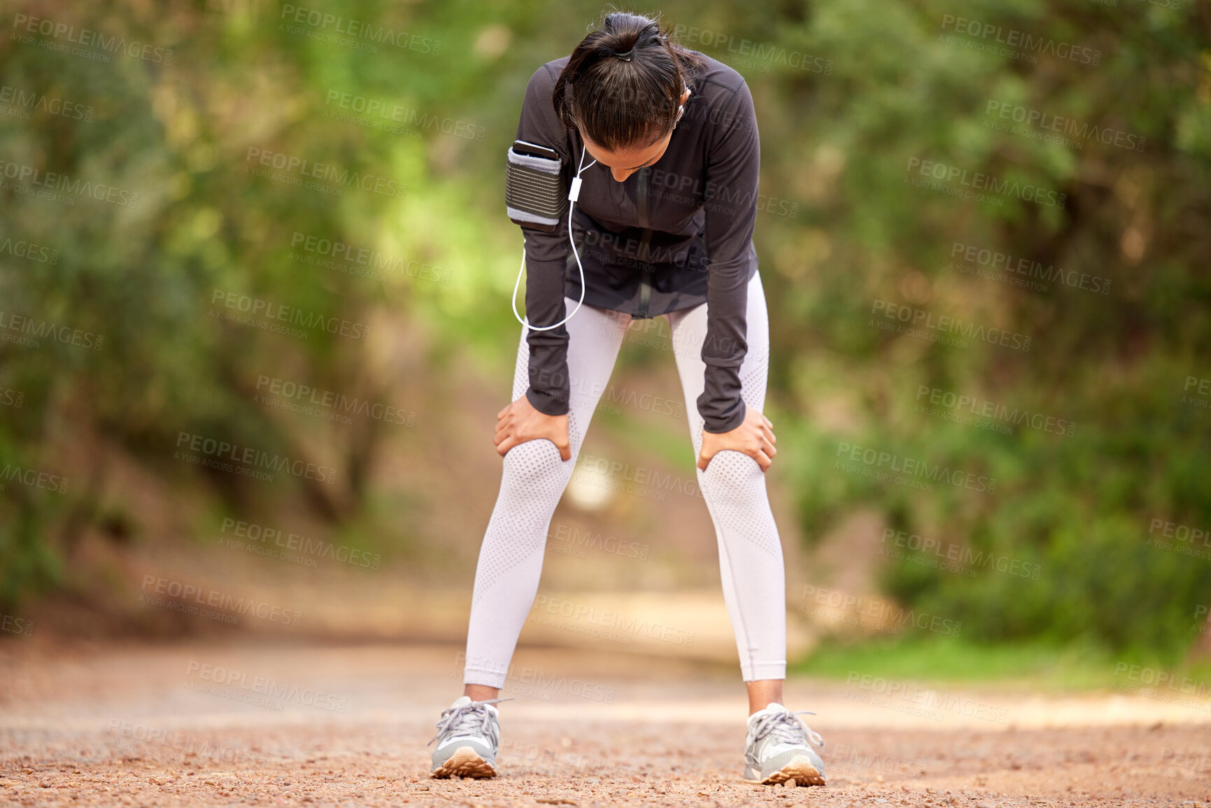 Buy stock photo Shot of a young woman taking a break while jogging through the forest