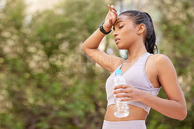 Buy stock photo Shot of a sporty young woman having looking tired while drinking water outdoors