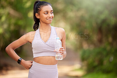 Buy stock photo Shot of a sporty young woman drinking water while exercising outdoors
