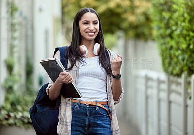 Buy stock photo Student, girl and fist pump on campus with smile, headphones and books for learning, development and study. Female person, happy and university for class, course and success in exam for education