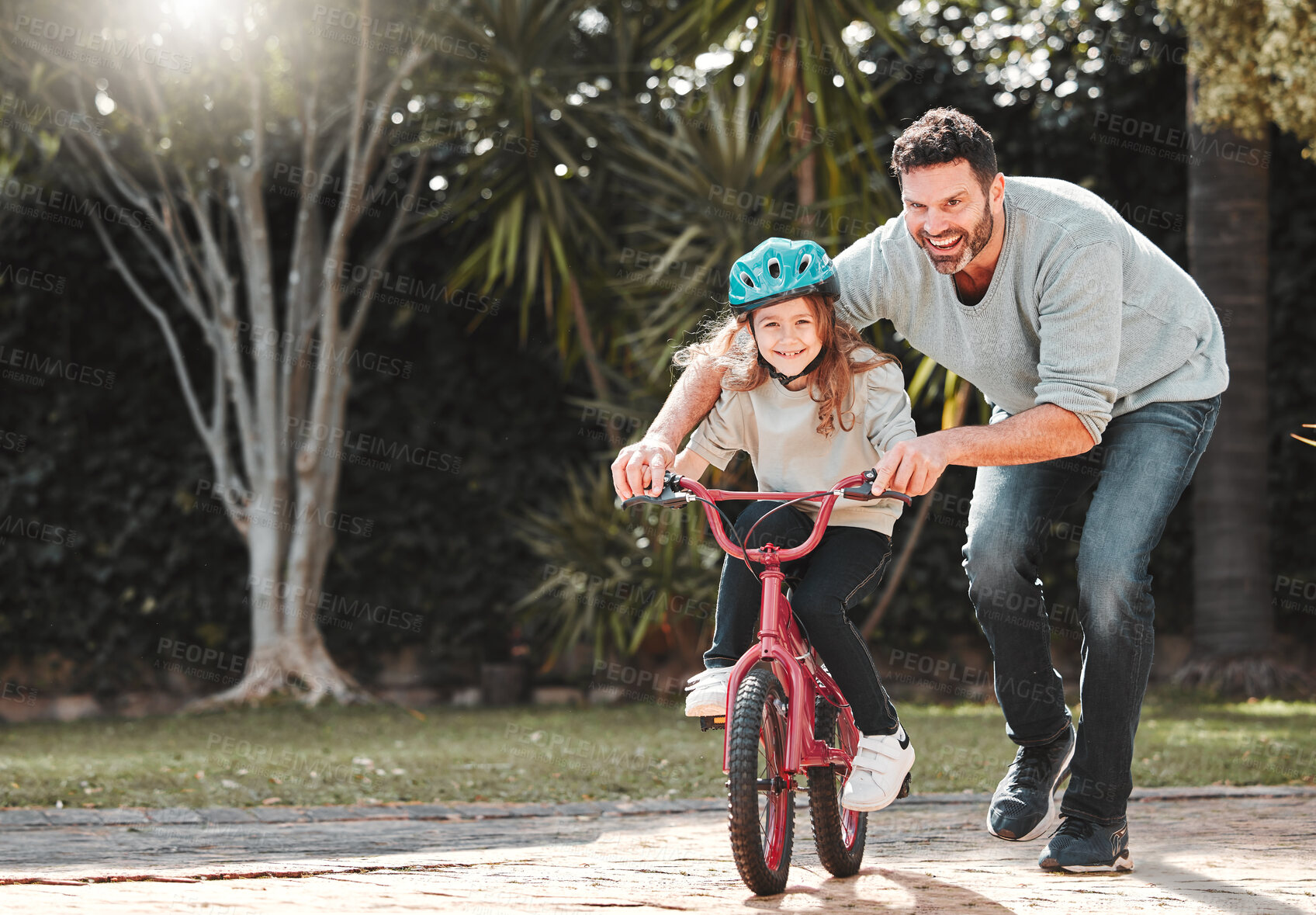 Buy stock photo Shot of a man assisting his daughter while riding a bicycle