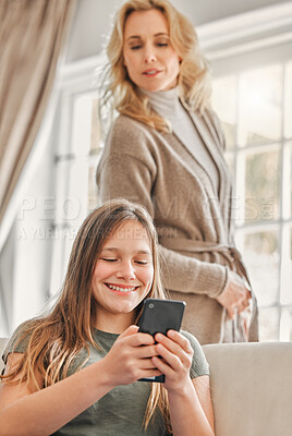 Buy stock photo Shot of a mature mother sneakily checking what her daughter's doing on her phone at home